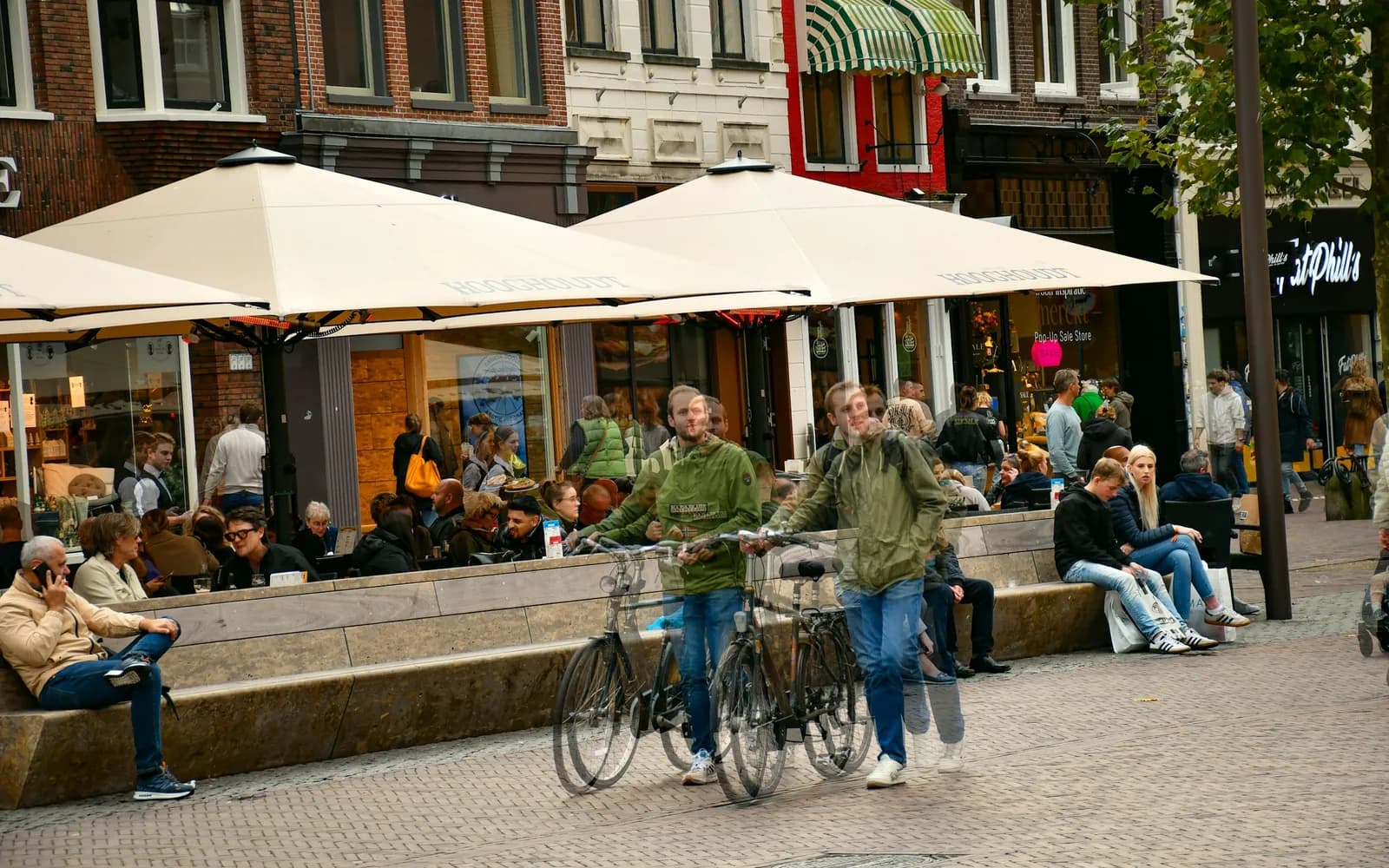 Volle terrassen onder parasols in de binnenstad van Groningen, met fietsers op de voorgrond
