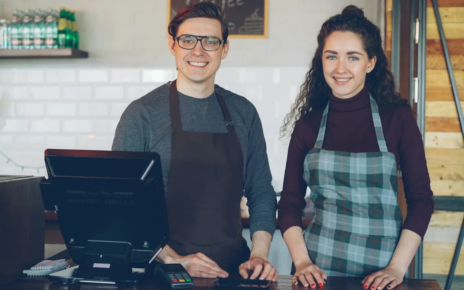 Twee lachende medewerkers achter de toonbank van een koffiezaak